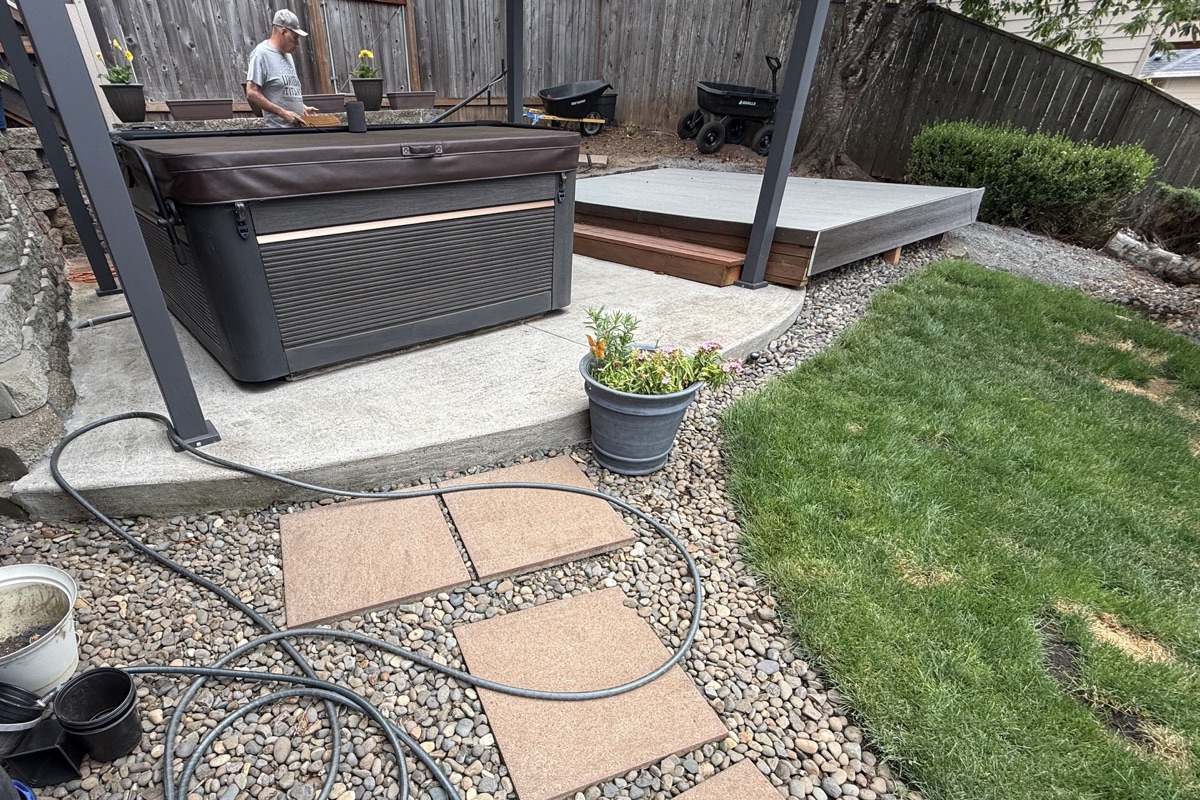 Covered hot tub on a concrete pad in a fenced backyard